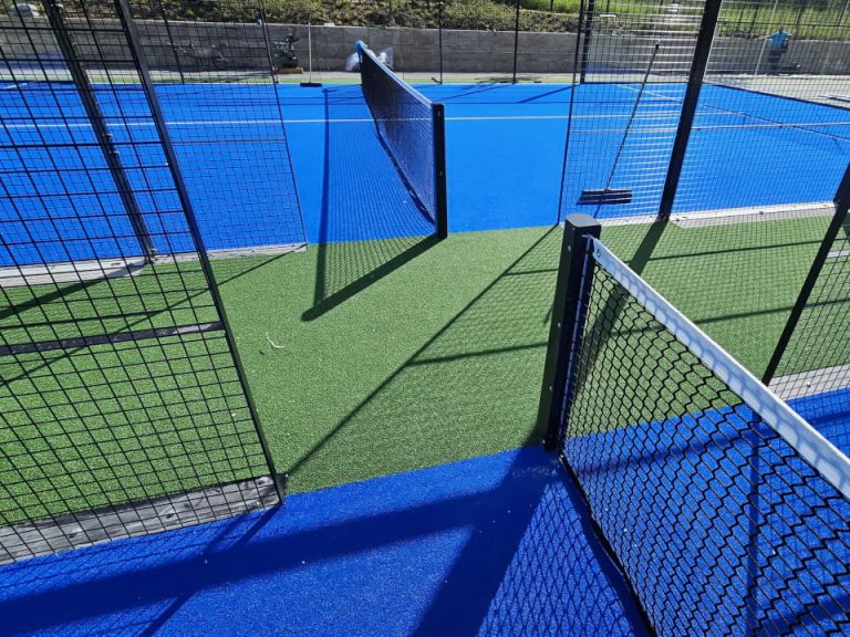 Padelplatz mit blauem Spielbelag, grünem Eingangsbereich und offenem Zugang