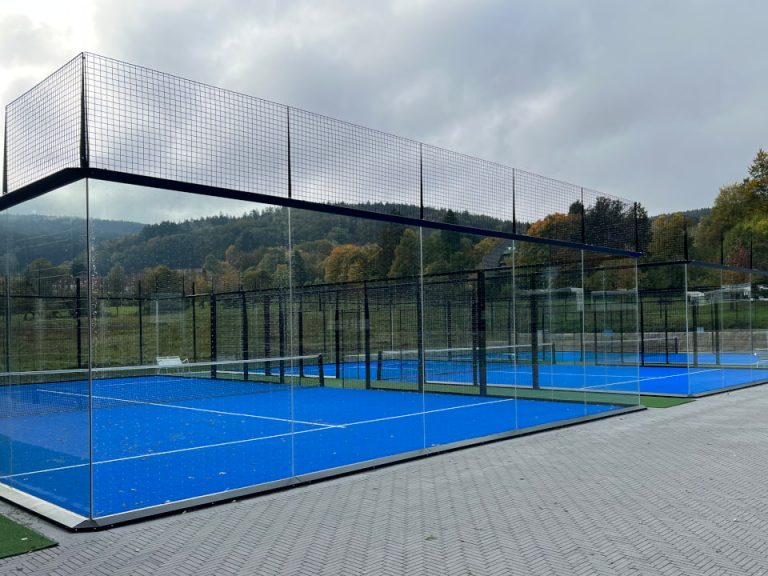 Outdoor-Padelplatz mit Glaswänden, schwarzer Stahlkonstruktion und blauem Spielbelag