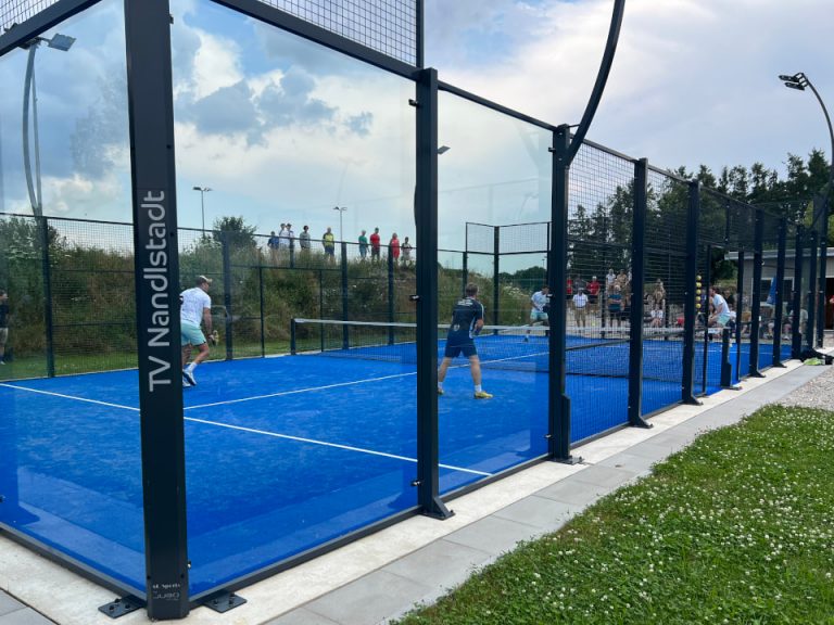 4 Spieler spielen im Padelcourt und liefern sich ein Match mit Zuschauern